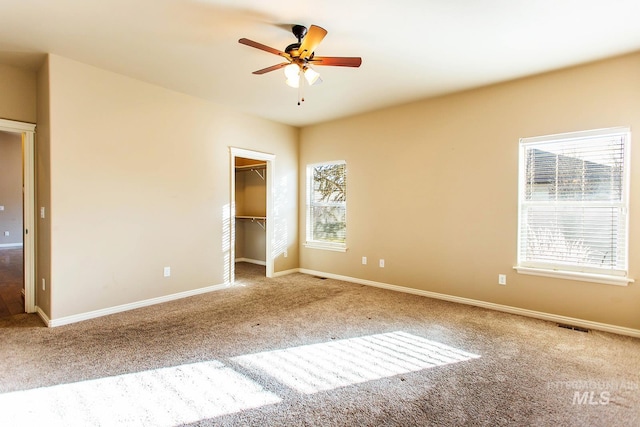 unfurnished bedroom with carpet flooring, ceiling fan, a closet, and a spacious closet