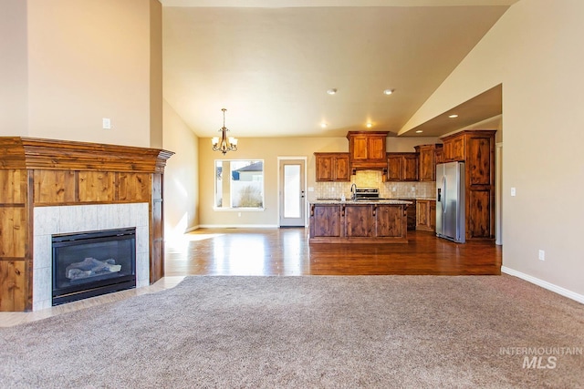 kitchen featuring a center island, stainless steel refrigerator with ice dispenser, backsplash, pendant lighting, and vaulted ceiling