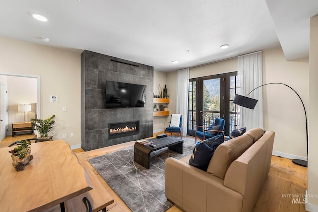 living room featuring a tiled fireplace and hardwood / wood-style floors