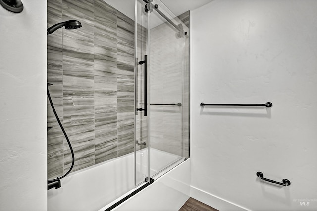 bathroom with hardwood / wood-style floors and shower / bath combination with glass door