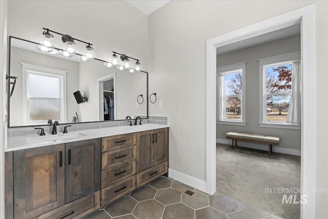 full bathroom with tile patterned flooring, a sink, baseboards, and double vanity