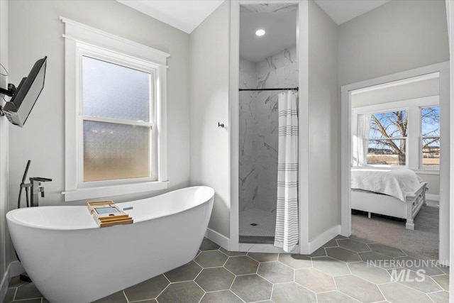 ensuite bathroom featuring a freestanding tub, connected bathroom, a shower stall, and baseboards