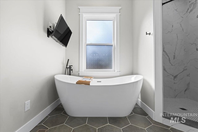 full bath with baseboards, a freestanding tub, a shower stall, and tile patterned floors