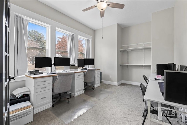 office featuring light colored carpet, ceiling fan, and baseboards