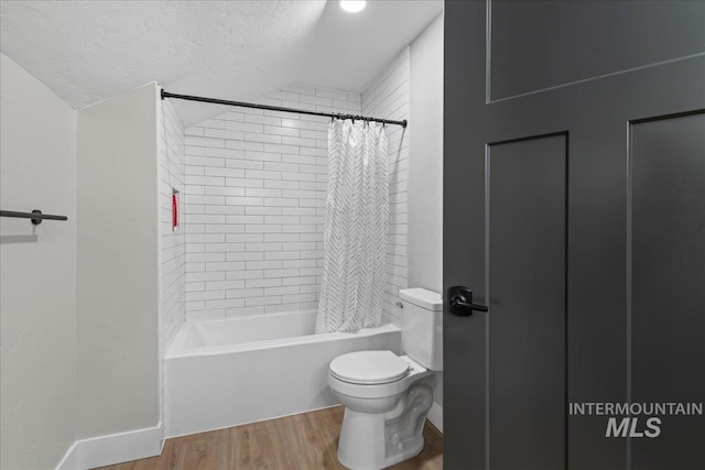 bathroom with a textured ceiling, toilet, wood finished floors, vaulted ceiling, and shower / bathtub combination with curtain