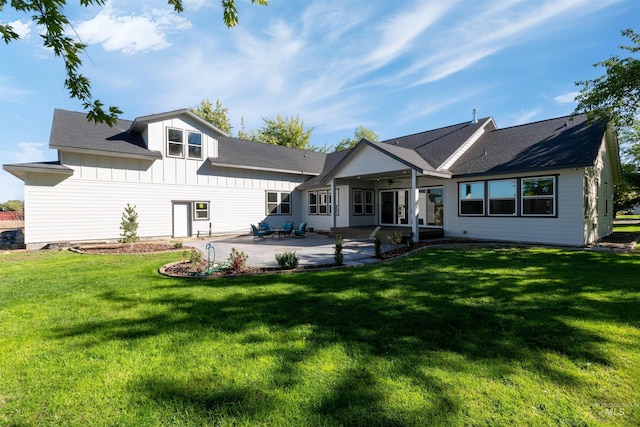 back of property with board and batten siding, a patio, and a lawn