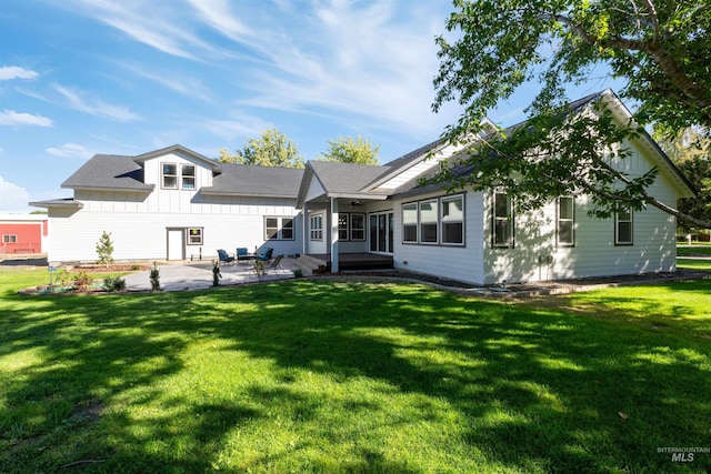 rear view of house with a patio, a yard, and board and batten siding