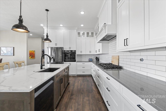 kitchen with a center island with sink, stainless steel fridge with ice dispenser, custom range hood, glass insert cabinets, and gas cooktop