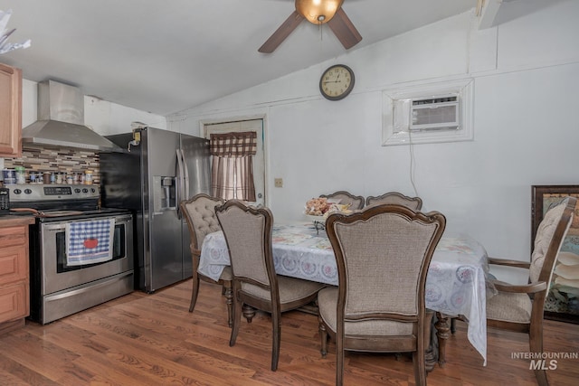 dining room featuring a wall unit AC, ceiling fan, vaulted ceiling, and dark hardwood / wood-style floors