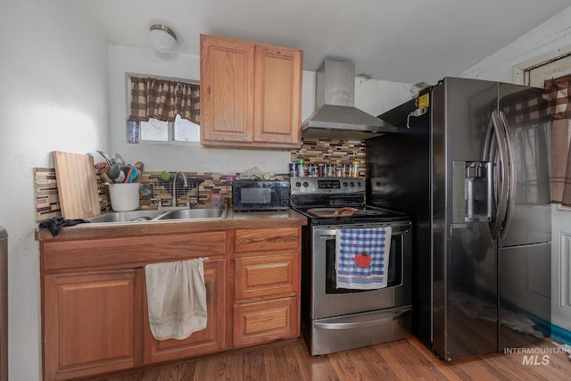 kitchen featuring sink, wall chimney exhaust hood, backsplash, hardwood / wood-style floors, and appliances with stainless steel finishes