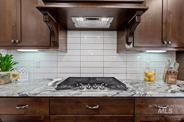 kitchen featuring stainless steel gas cooktop, dark brown cabinets, and light stone counters