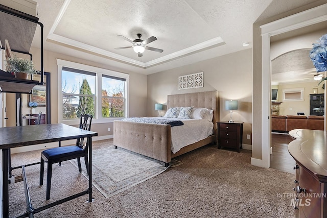 carpeted bedroom with a tray ceiling, baseboards, and a textured ceiling