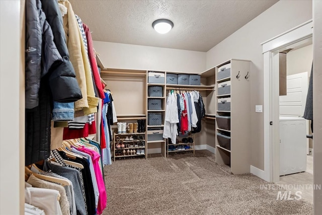 walk in closet featuring carpet and stacked washer / drying machine