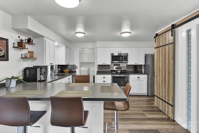 713 E Harcourt Rd, Boise, ID 83702 - kitchen featuring appliances with stainless steel finishes, a sink, a peninsula, dark countertops, and a barn door