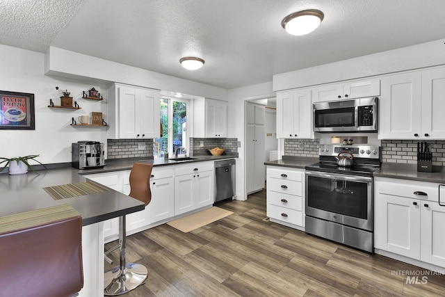 713 E Harcourt Rd, Boise, ID 83702 - kitchen featuring appliances with stainless steel finishes, a sink, open shelves, a textured ceiling, and dark countertops