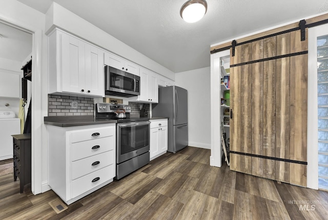 713 E Harcourt Rd, Boise, ID 83702 - kitchen featuring stainless steel appliances, washer / dryer, a barn door, dark countertops, and tasteful backsplash