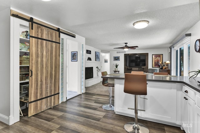 713 E Harcourt Rd, Boise, ID 83702 - kitchen featuring dark countertops, a ceiling fan, a brick fireplace, a peninsula, and white cabinetry