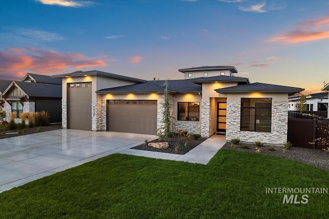 prairie-style home with a garage, driveway, fence, and stucco siding