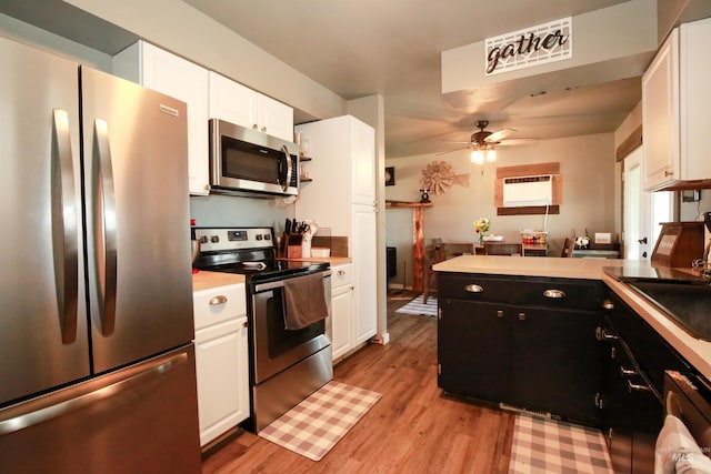 kitchen with light wood-type flooring, ceiling fan, stainless steel appliances, sink, and white cabinetry