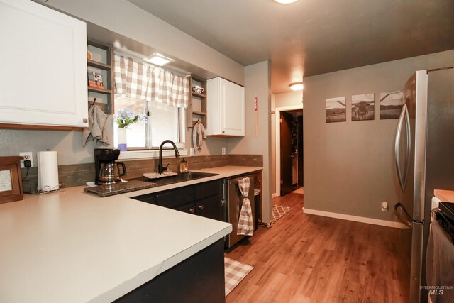 kitchen featuring light hardwood / wood-style floors, dishwashing machine, white cabinets, range, and sink