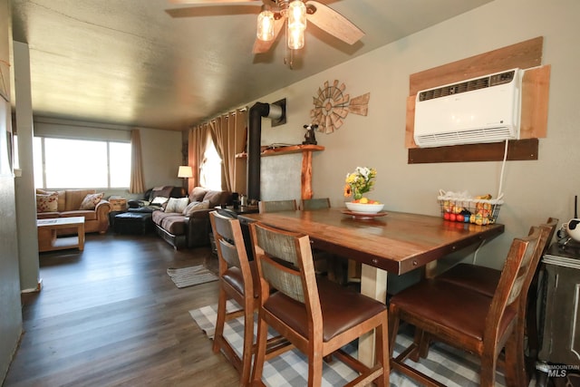 dining space with ceiling fan, dark wood-type flooring, a wood stove, and a wall unit AC