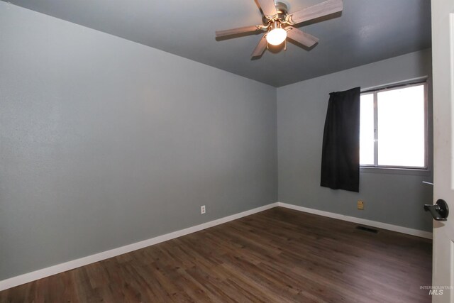 empty room with ceiling fan and dark hardwood / wood-style flooring