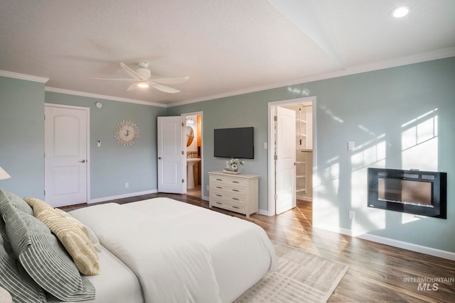 bedroom featuring ornamental molding, ensuite bath, wood finished floors, and baseboards