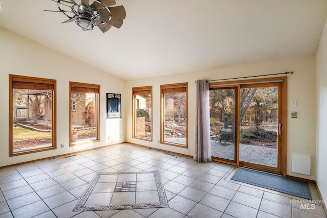 interior space with lofted ceiling, light tile patterned floors, ceiling fan, and baseboards