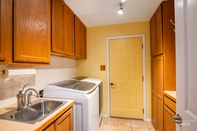 laundry room featuring light tile patterned floors, separate washer and dryer, a sink, baseboards, and cabinet space