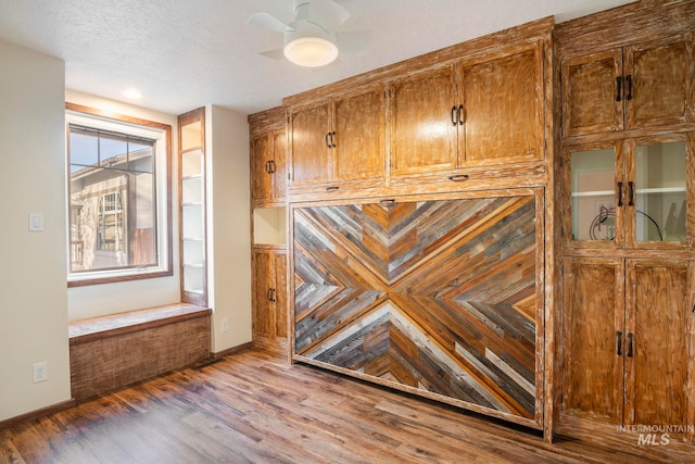 interior details featuring ceiling fan, a textured ceiling, baseboards, and wood finished floors