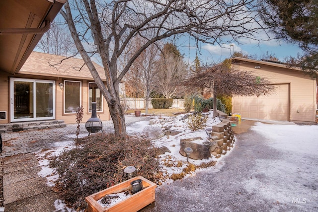 snowy yard featuring a garage and fence