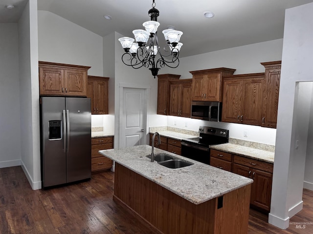 kitchen featuring appliances with stainless steel finishes, decorative light fixtures, sink, a kitchen island with sink, and light stone countertops