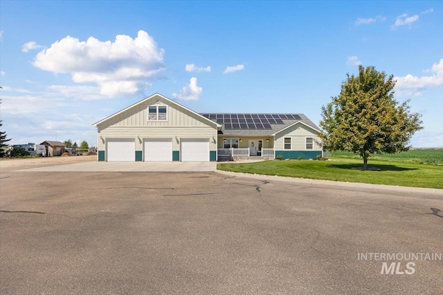 3415 Marble Front Rd, Caldwell, ID 83605 - view of front of house featuring board and batten siding, roof mounted solar panels, asphalt driveway, a front lawn, and an attached garage