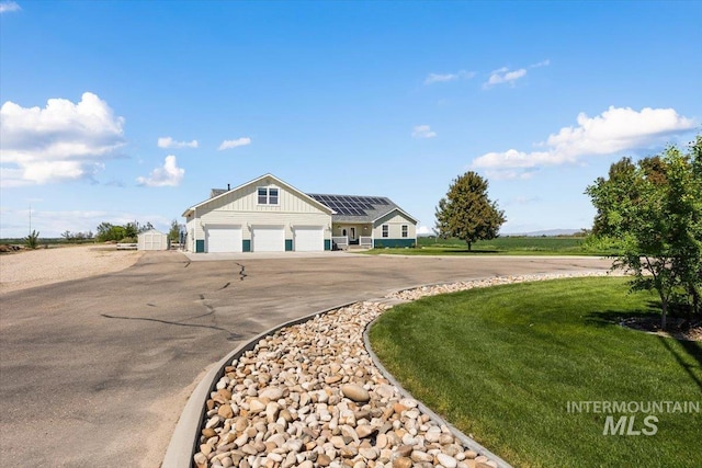 3415 Marble Front Rd, Caldwell, ID 83605 - view of front of property with asphalt driveway, roof mounted solar panels, a garage, board and batten siding, and a front yard