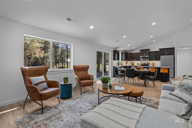 living room with light hardwood / wood-style floors and vaulted ceiling