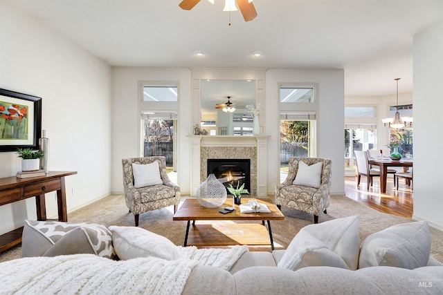 living room featuring ceiling fan with notable chandelier and light carpet