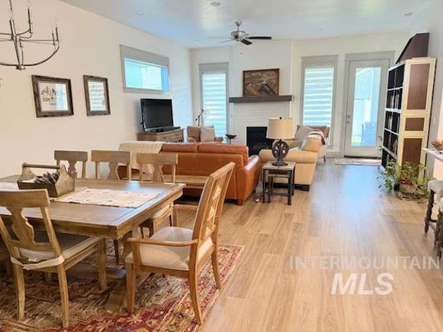 11703 W Amsonia, Star, ID 83669 - dining room with light wood-type flooring, a chandelier, a ceiling fan, and a fireplace