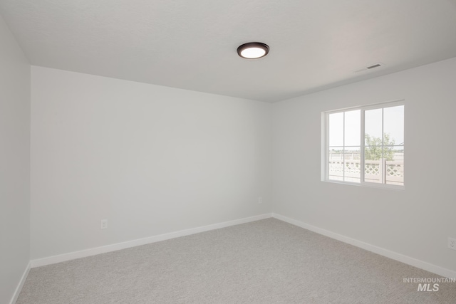 carpeted spare room with visible vents and baseboards