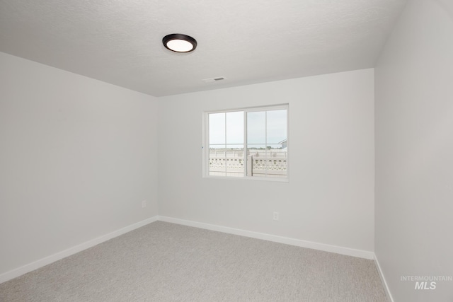 carpeted empty room with a textured ceiling and baseboards