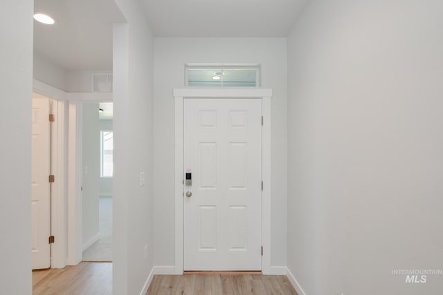 foyer with light wood-type flooring, visible vents, and baseboards