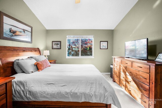 bedroom featuring light colored carpet, vaulted ceiling, and ceiling fan