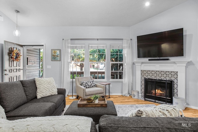 living room with a tile fireplace and hardwood / wood-style floors