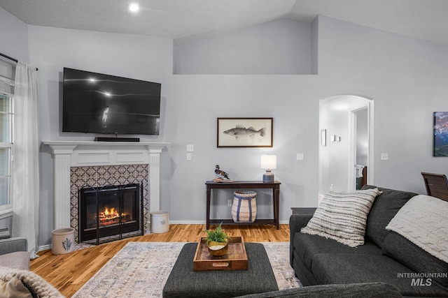 living room featuring light hardwood / wood-style floors, lofted ceiling, and a tile fireplace