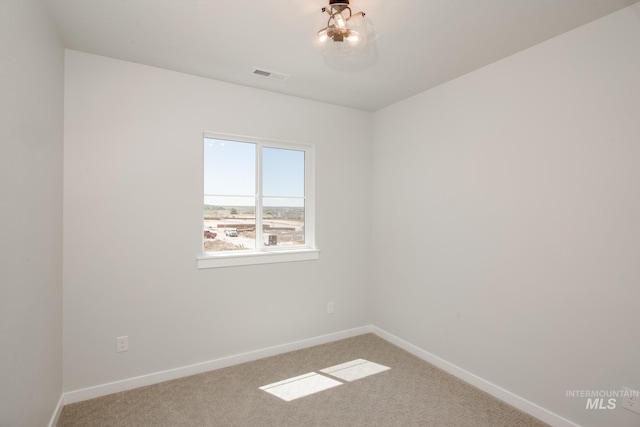 spare room featuring carpet, visible vents, and baseboards