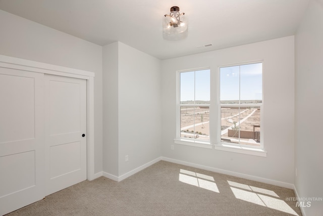 spare room with light carpet and baseboards