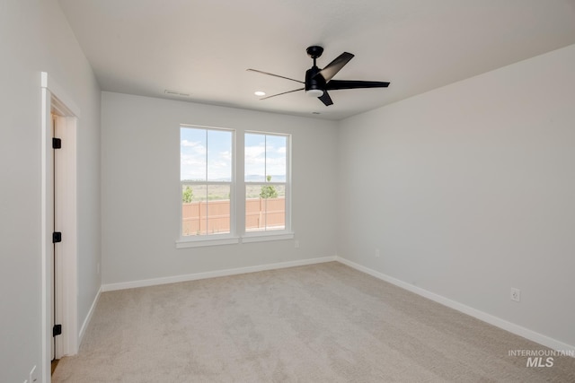 empty room with a ceiling fan, light carpet, and baseboards