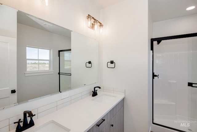 bathroom featuring a sink, a shower stall, and double vanity