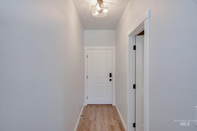 hall with light wood-style floors and baseboards