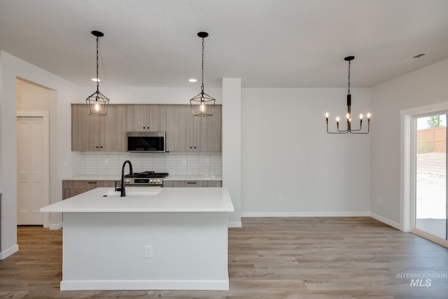 kitchen with light countertops, stainless steel microwave, a sink, and hanging light fixtures