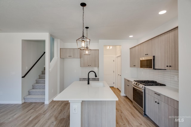 kitchen with a center island with sink, appliances with stainless steel finishes, light countertops, light brown cabinets, and a sink